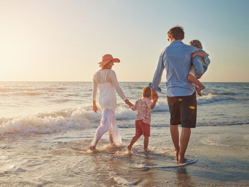 Family,,Beach,Walk,And,Back,With,Dad,Holding,Child,For